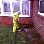 engineer in yellow suit doing drain jetting outside house